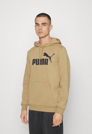 Felpa con cappuccio color sabbia, caratterizzata da un grande logo nero "PUMA" e un grafiche di pantera che salta. Presenta una tasca a marsupio e polsini a costina.