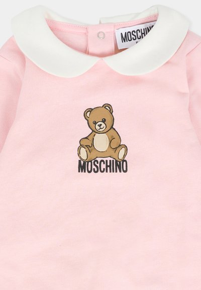 T-shirt in cotone rosa con colletto bianco a Peter Pan, caratterizzato da una grafica di un orso cartone e il testo "MOSCHINO" in nero sotto l'immagine.
