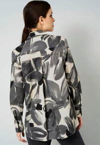 Langarmhemd aus leichtem Material mit einem großen abstrakten schwarzen und grauen Blumenmuster. Enthält eine Rückenfalte und geknöpfte Manschetten.