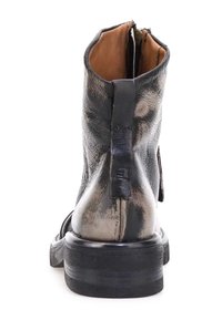 Musta nahkainen nilkkabooti, jossa on sileä pinta, pyöristetty kärki, takana vetoketju ja paksu musta ulkopohja.