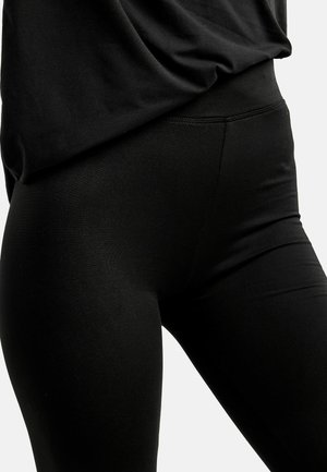 Mustad retuusid, sileda tekstuuriga, kõrge vöökohaga ja tihedalt istuva lõikega. Õmbluste detailid rõhutavad kuju, säilitades samal ajal minimalistliku stiili.