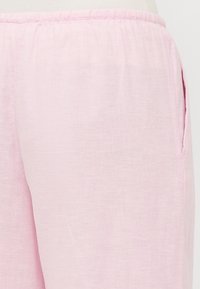 Pantaloni in lino rosa chiaro con una consistenza morbida, dotati di una cintura elasticizzata e tasche laterali per una maggiore utilità.