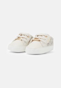 Zapatillas de lona blancas con detalles dorados, que cuentan con una suela de goma, diseño con cordones y un logotipo en un patrón sutil en los laterales.