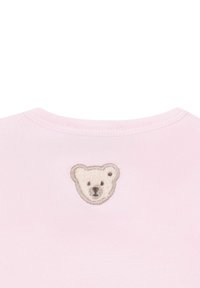 T-shirt rosa chiaro con un piccolo viso di orso ricamato sul retro. Tessuto morbido con scollatura rotonda e superficie liscia.