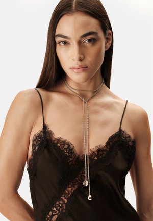 Zwart slipjurkje met kanten bies en spaghetti bandjes, met een gladde satijntextuur. Een gelaagde zilveren ketting met twee hangers hangt sierlijk.