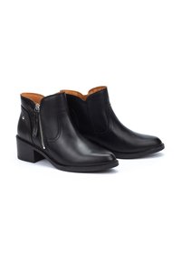 Botas de cuero negras hasta el tobillo con punta afilada y tacón bajo apilado. Cuentan con una cremallera lateral y textura suave. El interior es de color marrón claro.