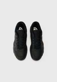 Black sneakers with a smooth leather upper featuring perforated details. Lace-up design and textured rubber sole. Logo on inner tongue.