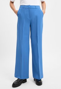 Blauwe wijde broek van soepel materiaal, met een op maat gemaakt ontwerp, zijkanten met zakken en een relaxed fit. Verfraaid met een strakke tailleband.