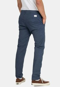 Navy blue trousers with a relaxed fit, elastic waistband, side and back pockets, and a fabric label on the back. Textured fabric.