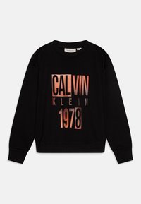 Svart hettegenser med en iøynefallende, metallisk rosagull grafikktrykk med "CALVIN KLEIN" og "1978", rund halslinning, og ribbede mansjetter.