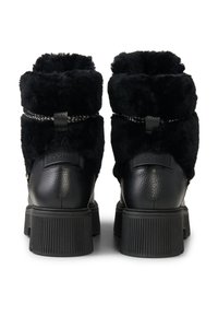 Czarne botki za kostkę z kołnierzem z syntetycznego futra, skórzaną cholewką, okrągłym noskiem i teksturowaną, grubą gumową podeszwą. Posiadają dekoracyjną plecioną taśmę.