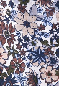 Tessuto floreale con uno sfondo bianco, caratterizzato da grandi fiori beige, blu e rossi, con foglie verdi e motivi intricati.