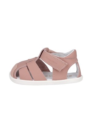 Sandalia rosa para niño pequeño con punta cerrada, tira ajustable de velcro y suela blanca, diseñada para comodidad y soporte.