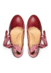Chaussures en cuir rouge avec des bords festonnés, intérieur beige et lacets à motifs rouge et blanc. Présente des détails cousus le long des bords.