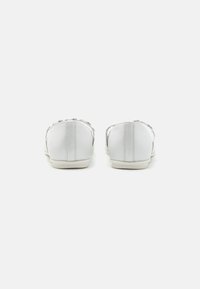 Weiße Sneakers aus glattem Leder, niedrig geschnittenes Design, minimalistische Silhouette und kontrastierende graue Akzente an den Seiten und um die Schnürsenkel.