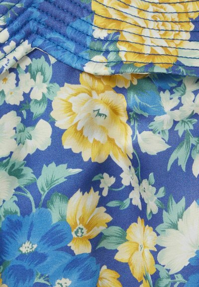 Tessuto floreale con grandi fiori gialli e blu su uno sfondo blu, con foglie verdi. La texture sembra morbida e ha una finitura liscia.