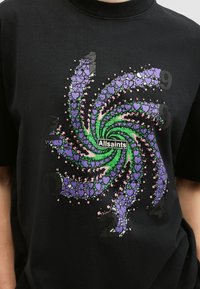 Svart t-shirt med en färgglad spiraldesign av hjärtan i grönt, lila och rosa, med texten "Allsaints" i mitten.