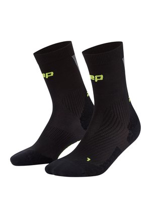Socks sportivi neri con design testurizzato, polsini a coste e accenti riflettenti. Presentano il logo giallo sui lati e aree della punta rinforzate.