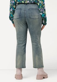 Vaaleansiniset farkut, joissa suora leikkaus, kahdella takataskulla ja hienovaraisella kulutuksella. Yhdistetty vaaleanpunaisten nilkkasaappaiden kanssa.