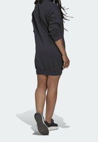 Mörkgrå sweatshirtklänning med insydd nederkant, långa ärmar och ribbade muddare, tillsammans med svarta sneakers med en strukturerad sula.