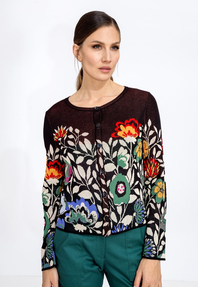 Cardigan en tricot avec un motif floral en fils multicolores sur un fond sombre, avec un col rond et une fermeture à boutons.