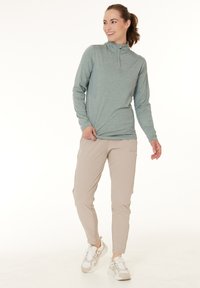 Lys blå langærmet halv-zip top med en tekstureret brystpanel, parret med beige cargo bukser og hvide sneakers. Glat, åndbart materiale.