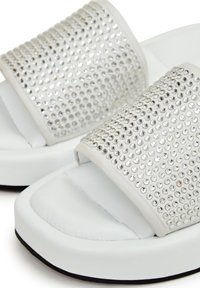 Sandales à plateforme blanches avec larges brides décorées de plusieurs rangées de petits strass ronds argentés.