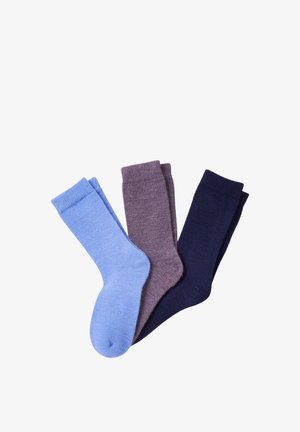 Trois paires de chaussettes en laine pliées, disposées côte à côte en bleu clair, violet et bleu marine foncé sur un fond blanc.