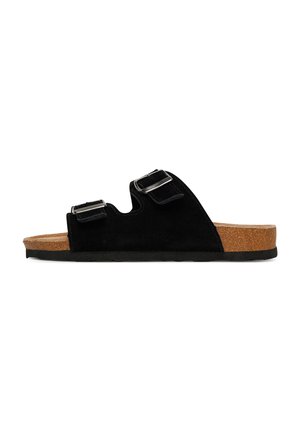 Schwarze Slide-Sandale mit zwei verstellbaren Schnallenriemen, Kork-Fußbett und flacher schwarzer Sohle, seitlich auf weißem Hintergrund gezeigt.