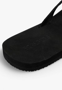 Infradito neri in gomma con suola texturizzata, dotate di una pianta liscia e di una cinghia in nylon intrecciato; presente il logo "SCALPERS" in rilievo.