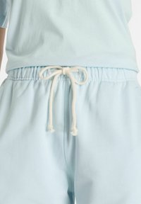 Shorts con elastico in vita azzurro chiaro e coulisse. Tessuto morbido, vestibilità rilassata e tasche laterali. Design semplice senza motivi.