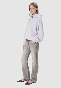 Haut de survêtement cropped gris clair avec capuche, associé à un jean gris clair. Complété par des ballerines à bout pointu avec imprimé animal. Look décontracté.