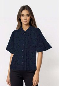 Navy blue short-sleeve shirt with a button-up design, featuring eyelet patterns and a classic collar. Soft, textured fabric.