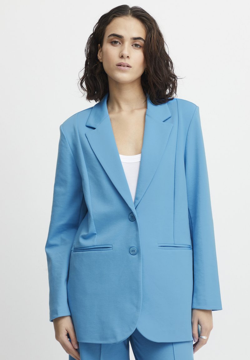 Lichtblauwe blazer gemaakt van zachte stof, met een klassieke revers, een enkele rij knopen, twee voorzakken en knoopsluiting.