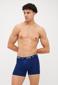 Námorníckomodré boxerky vyrobené z mäkkej látky, s širokým čiernym pásom so bielym logom "Nike" a priliehavým strihom pre pohodlie.