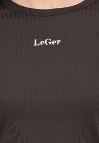 Μαύρο ριμπ τοπ με στρογγυλή λαιμόκοψη και μικρό ροζ λογότυπο «LeGer» στο κέντρο του στήθους. Λείο ύφασμα.