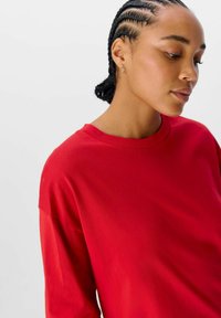 Rød bomulds T-shirt med rund halsudskæring og afslappet pasform. Har korte ærmer og en glat tekstur, fremhævet af en subtil glans.