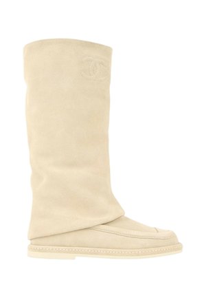 Botte beige en daim mi-mollet avec semelle plate et logo brodé près du haut sur fond blanc.