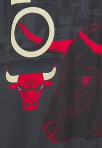 Sort T-shirt med rød kalv grafik, fed skrift og en struktureret design. Kalandens udtryk er fremtrædende med kontrasterende former.