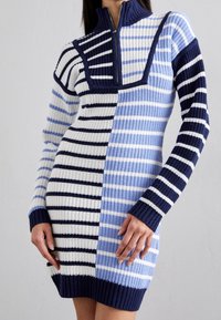 Robe tricotée présentant un mélange de rayures horizontales en marine, bleu clair et blanc ; col montant avec une fermeture éclair, silhouette ajustée, poignets côtelés.