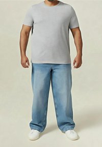 Šedé tričko s krátkým rukávem spárované se světle modrými džíny; volné, s měkkou texturou, nošené s bílými botami.