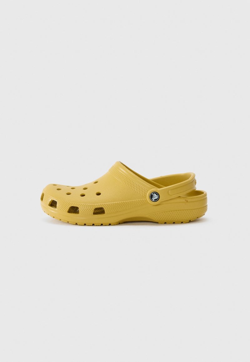 Sabot jaune à enfiler avec des trous de ventilation, semelle texturée et bride de talon ajustable sur un fond clair uni.