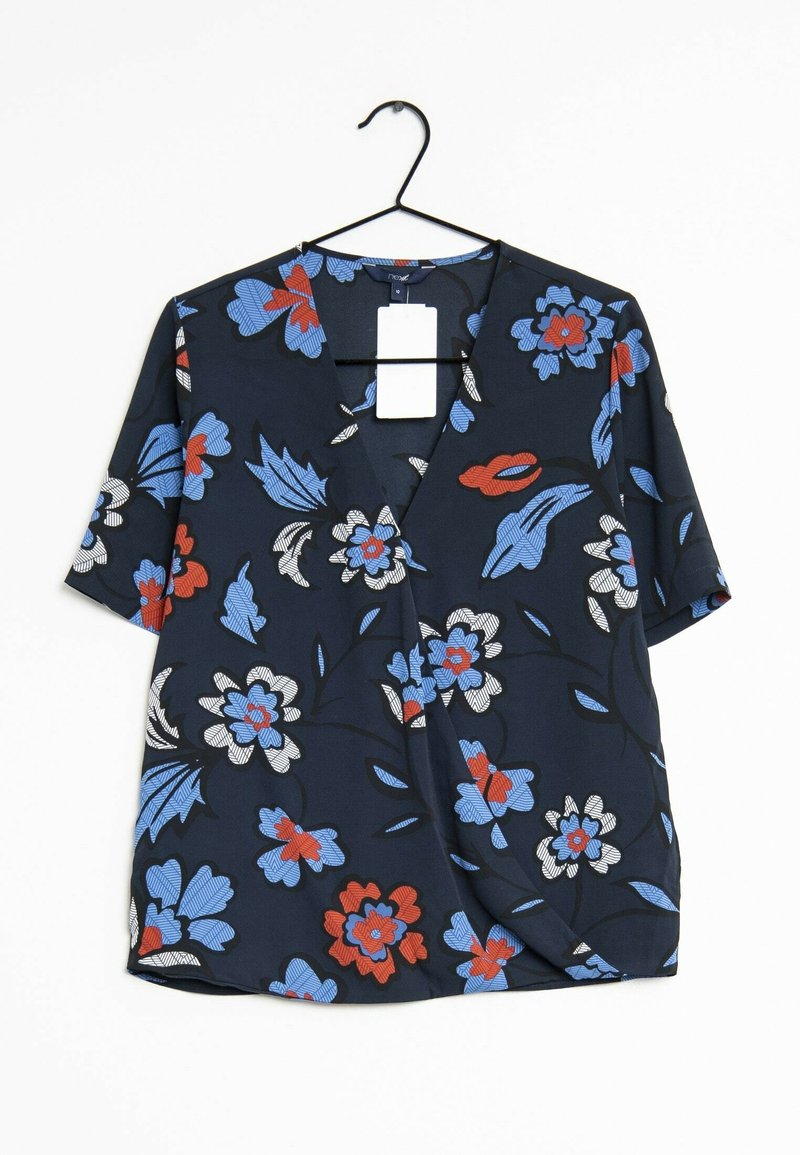 Blouse bleu marine à manches courtes avec un motif floral rouge, blanc et bleu, suspendue sur un cintre noir sur fond blanc.