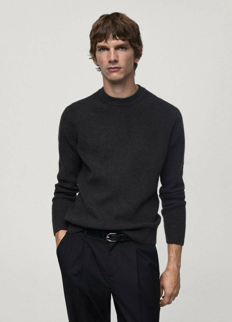 Dunkelgrauer Strickpullover mit Rundhalsausschnitt und langen Ärmeln, kombiniert mit schwarzen Hosen. Das Material wirkt weich und strukturiert.