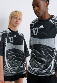 Two people wearing black and white Adidas sports jerseys with number 10, standing against a plain white background.