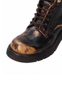 Černé a hnědé kožené kotníkové boty s drsnou texturou, kulatou špičkou a hnědými tkaničkami. Mají vzorovaný povrch a robustní podrážku.