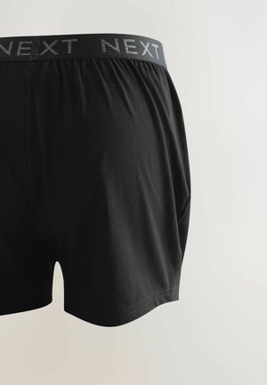Black cotton boxer shorts featuring a soft waistband with "NEXT" logo. The shorts have a relaxed fit and smooth texture.
