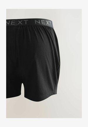 Crne pamučne bokserice s mekanim pojasom s logom "NEXT". Bokserice imaju opuštenu kroja i glatku teksturu.