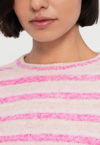 Πουλόβερ από φλις με οριζόντιες ρίγες σε ροζ και λευκό, με στρογγυλή λαιμόκοψη και μαλακή υφή.