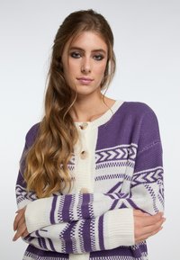 Stickad cardigan i lila och vitt, med ett geometriskt mönster, knappar framtill, ribbade ärmslut och en avslappnad passform.